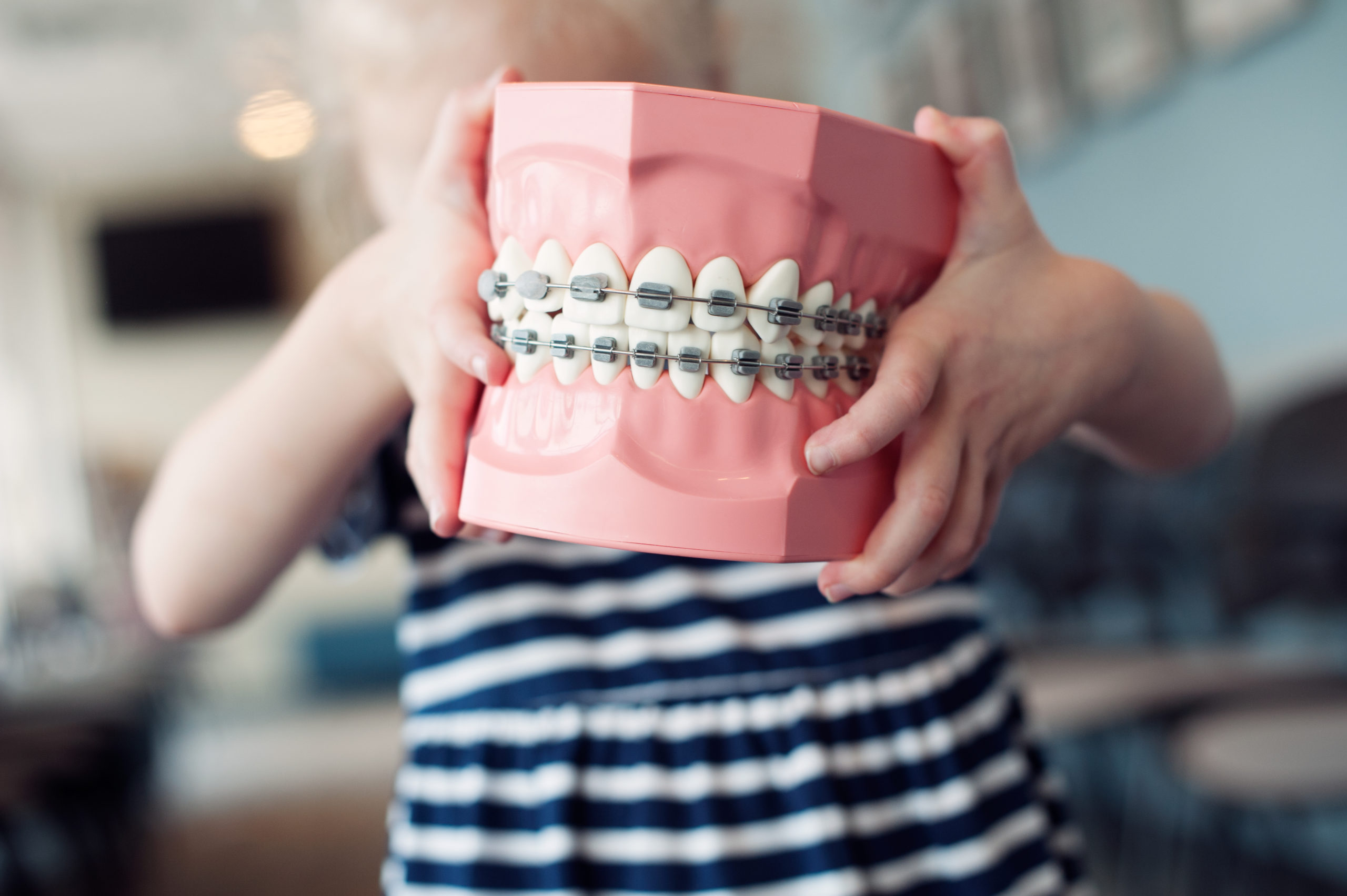 child holding 3D teeth with braces